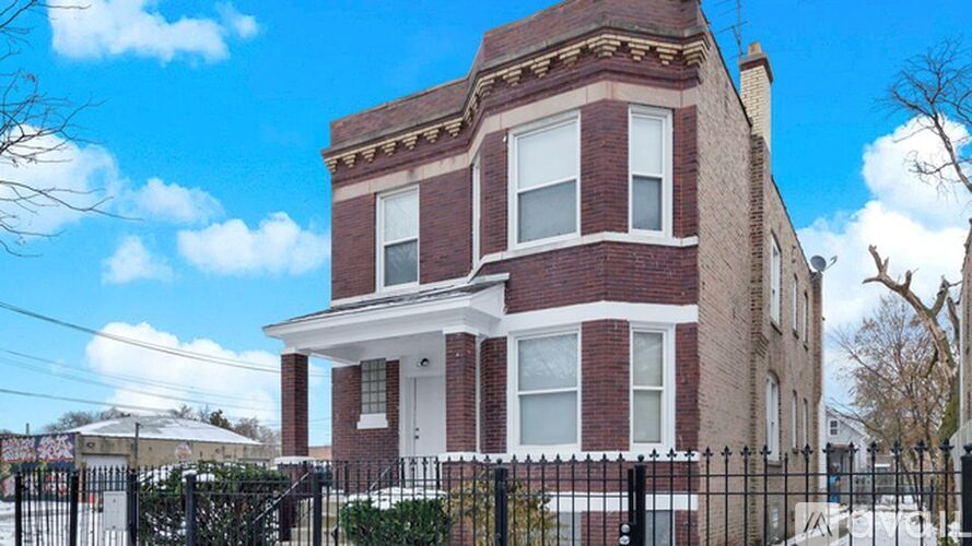 A red brick house with a black fence in front.