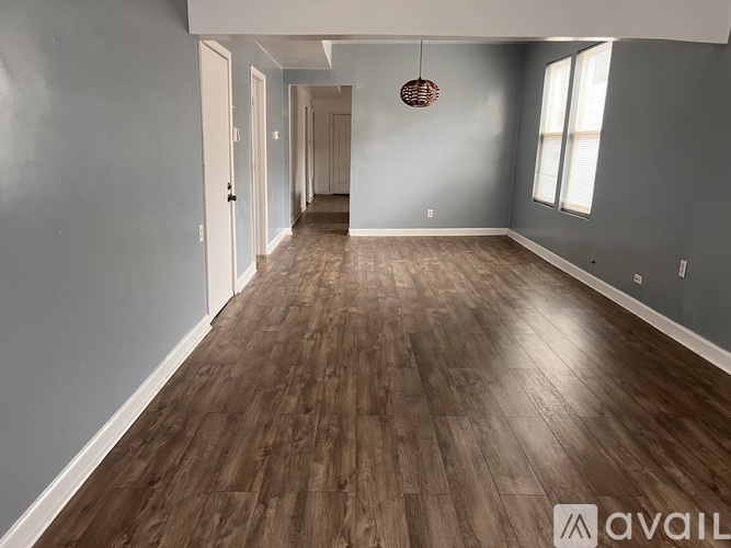 A spacious room with wooden flooring and a hanging light fixture.