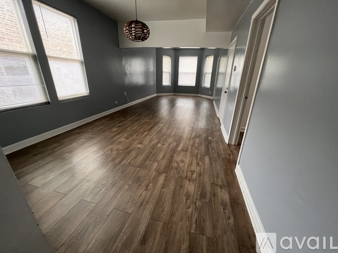 A room with wooden flooring and a hanging light fixture.