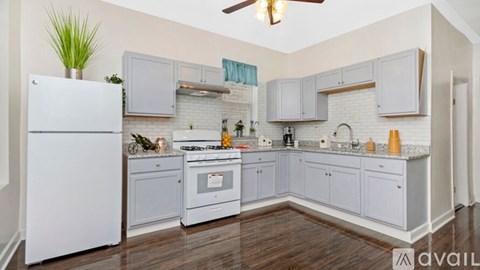 A kitchen with a white refrigerator and grey cabinets.