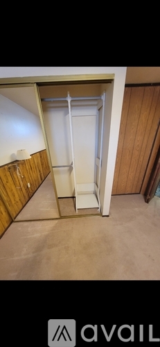 A white door is open in a room with wooden walls.