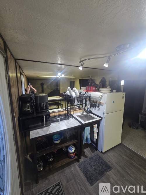 A small, cluttered kitchen with a sink, stove, and refrigerator.