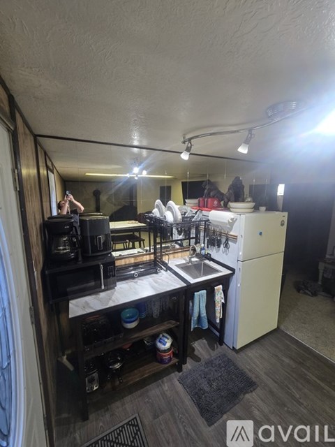 A small, cluttered kitchen with a sink, stove, and refrigerator.