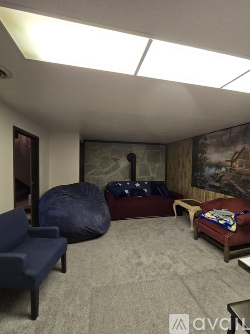 A living room with a blue chair, a round bean bag chair, a red couch, and a wooden coffee table.