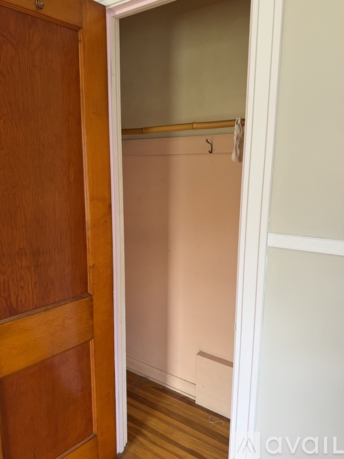 A wooden door is open to a white wall.