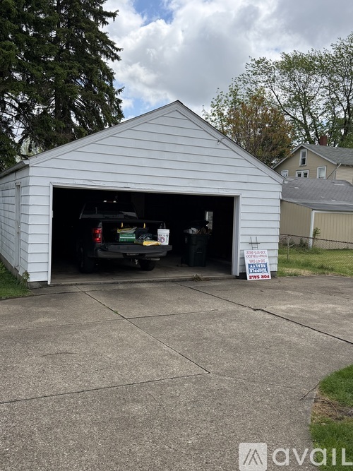 A white garage with a car inside and a sign on the ground.