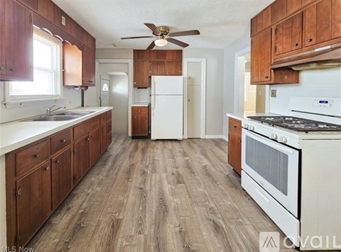 A kitchen with wooden cabinets and a white stove top oven.