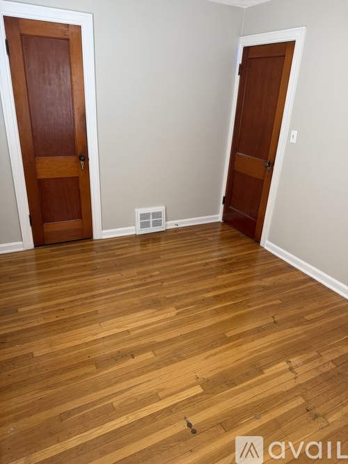 A room with wooden floors and two doors.