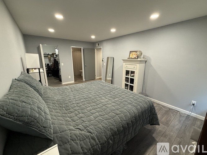 A bedroom with a large bed and a dresser in the corner.