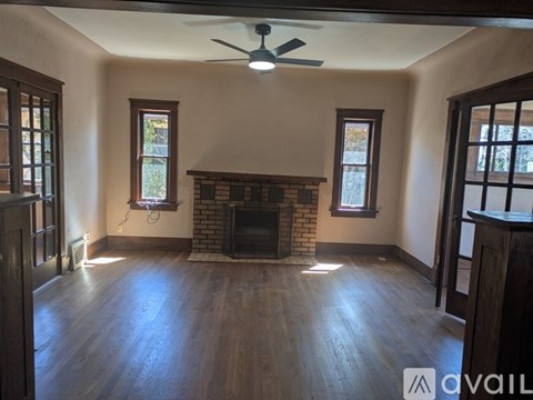A living room with a fireplace and a ceiling fan.