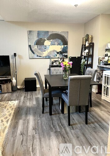 A dining room with a table set for two and a painting on the wall.