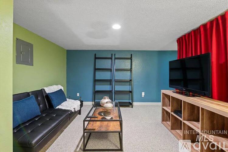 A living room with a black couch, a wooden coffee table, and a red curtain.