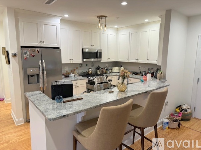 A kitchen with a granite countertop and two chairs.