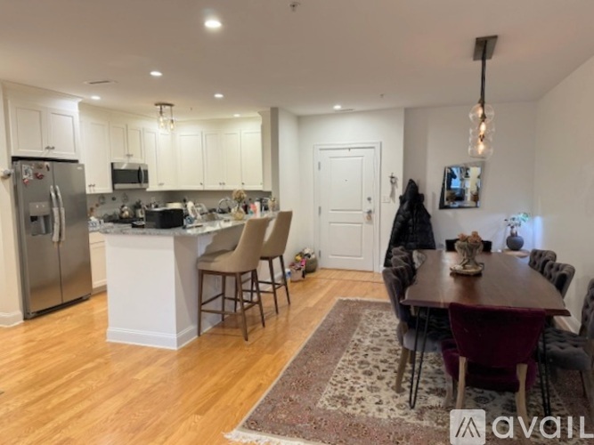 A kitchen with a refrigerator, a dining table with chairs, and a countertop with a microwave.