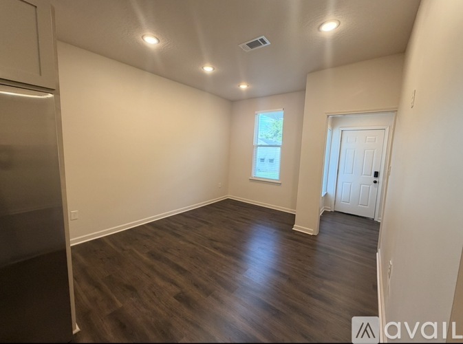 A spacious room with wooden flooring and white walls.