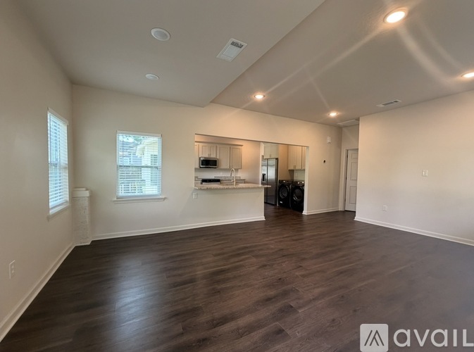 A spacious room with wooden flooring and a large mirror on the wall.