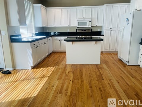 A kitchen with white cabinets and a wooden floor.