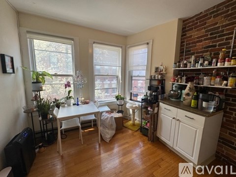 A kitchen with a white table and chairs, a white cabinet, and a brick wall.