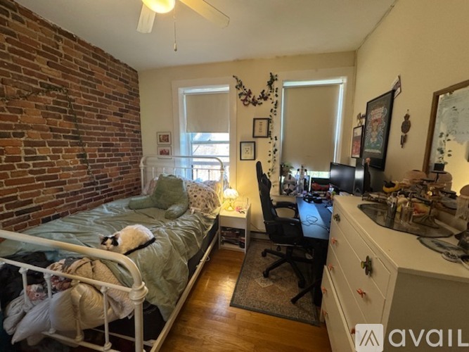 A bedroom with a brick wall and a bed with a green blanket.