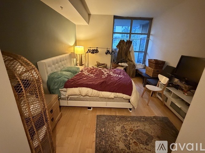 A bedroom with a bed, a chair, and a television.