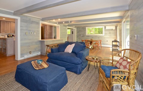 A living room with a blue couch and a wicker chair.