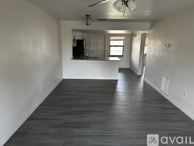 A spacious room with wooden flooring and white walls.