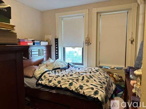 A bedroom with a bed, dresser, and window.