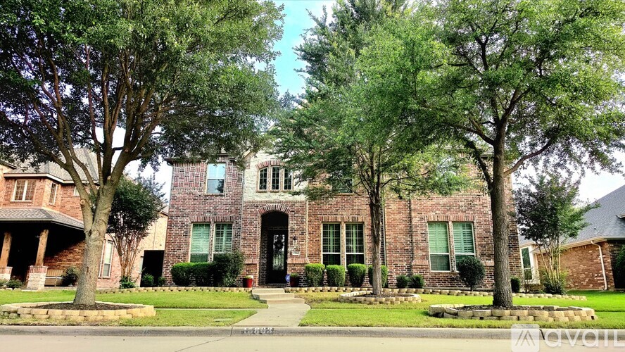 A brick house with a black door and windows surrounded by trees.