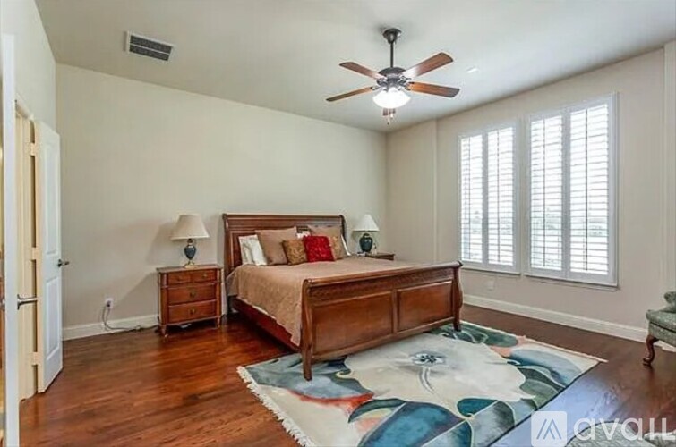 A bedroom with a bed, nightstands, and a ceiling fan.