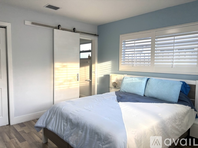 A bedroom with a bed, a mirror, and a sliding door.