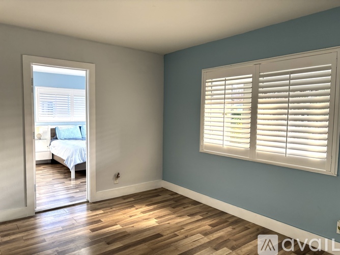 A bedroom with a bed and a window with blinds.