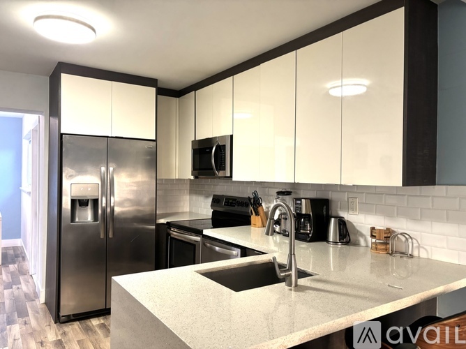 A modern kitchen with a stainless steel refrigerator and white cabinets.