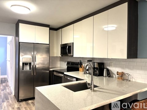 A modern kitchen with a stainless steel refrigerator and white cabinets.