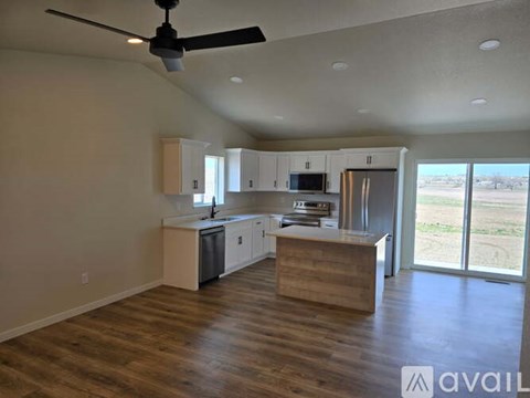 A spacious kitchen with a ceiling fan and wooden flooring.