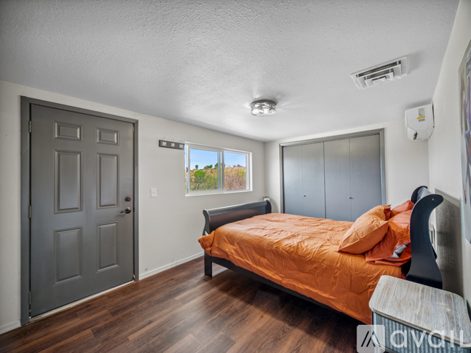 A bedroom with a bed, dresser, and window.
