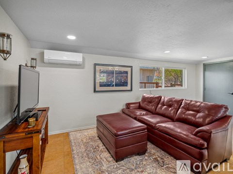 A living room with a red leather couch and a television on a wooden stand.