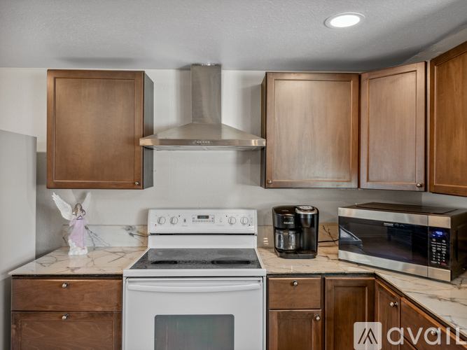 A kitchen with a white stove top oven, a microwave, and wooden cabinets.
