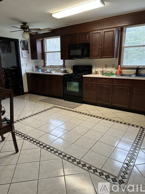 A kitchen with brown cabinets and a black stove top oven.