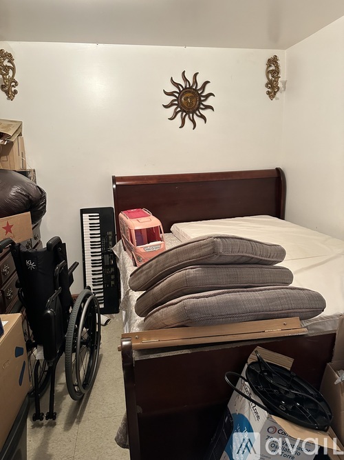 A room with a bed, a wheelchair, and a box with a star on it.