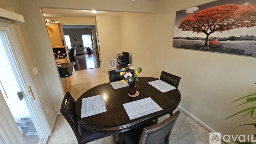 A dining room with a table set for four and a painting of a tree on the wall.