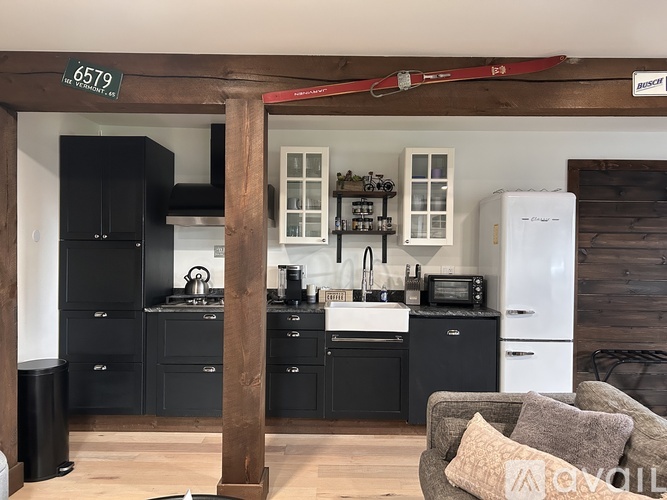 A kitchen with black cabinets and a white fridge.