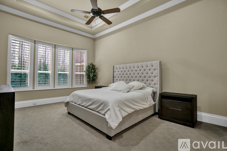 A bedroom with a bed, nightstand, and a ceiling fan.
