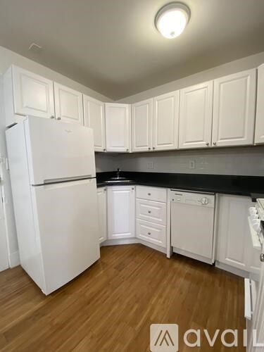 A kitchen with white cabinets and a white fridge.