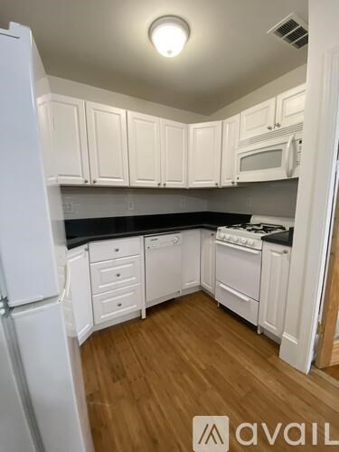 A kitchen with white cabinets and appliances.