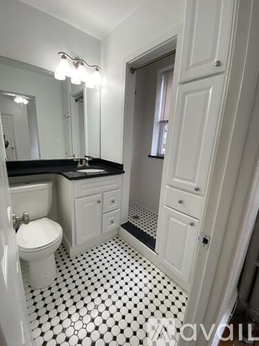 A white toilet sits in a bathroom with black and white tiles.