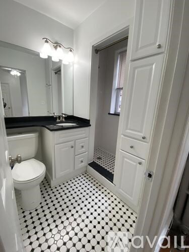 A white toilet sits in a bathroom with black and white tiles.