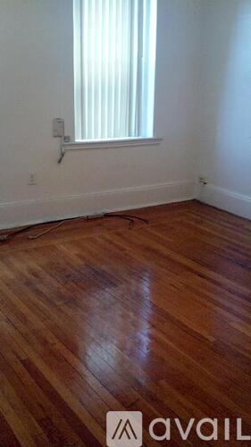 A room with wooden flooring and a window with blinds.