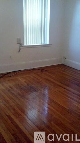 A room with wooden flooring and a window with blinds.