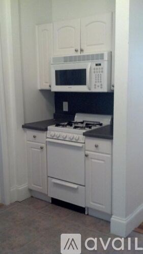 A kitchen with white cabinets and a black countertop.