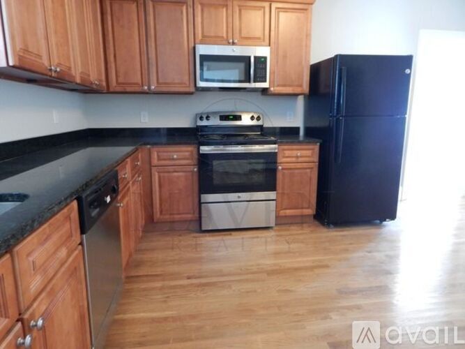 A kitchen with wooden cabinets and black countertops.